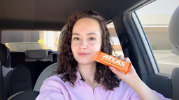 Woman holding an orange Atlas bar inside a car